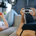 Dwie kobiety na kanapie grają w konsolę na imprezowym spotkaniu